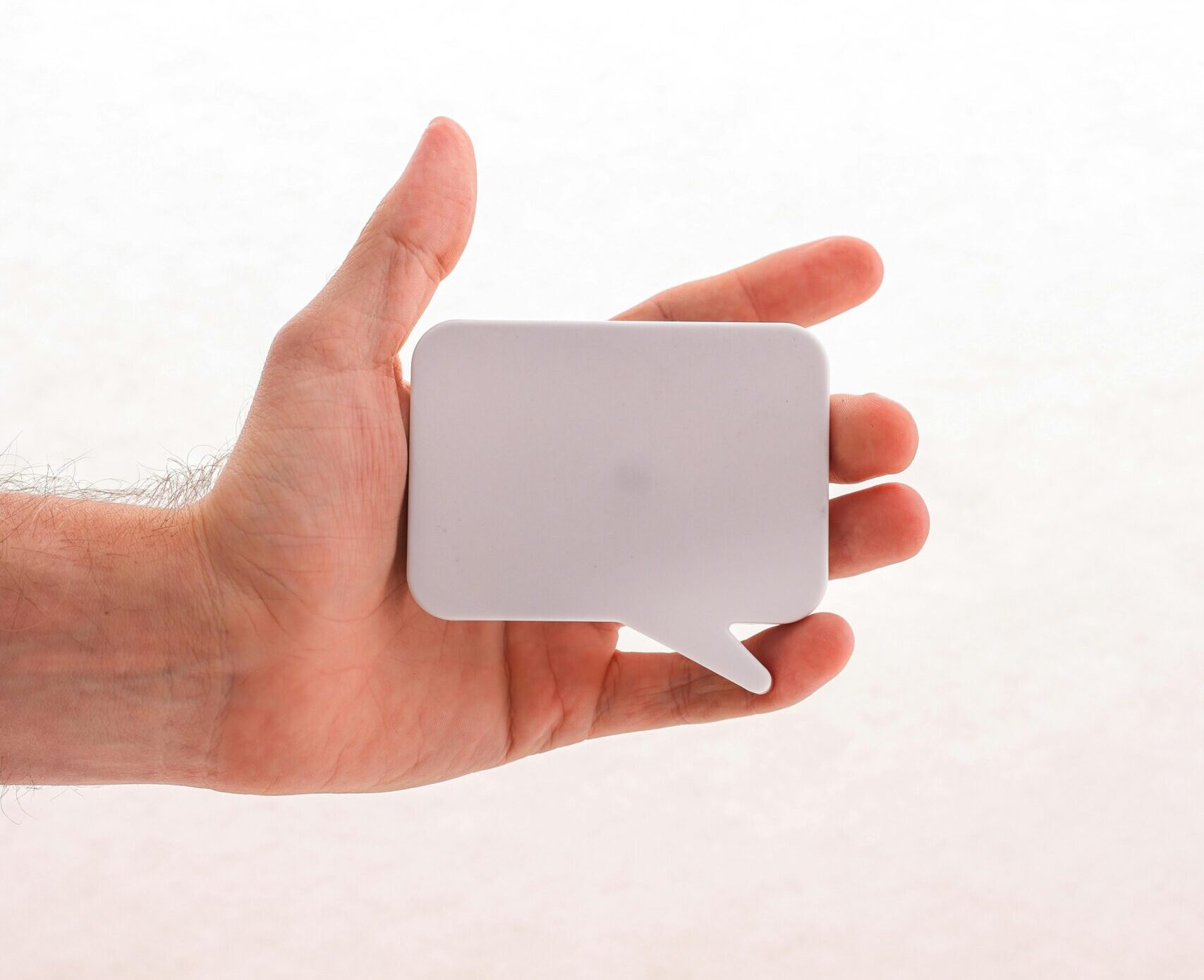 INICIO A hand holding a blank white speech bubble sticker, perfect for mockups or conceptual designs.